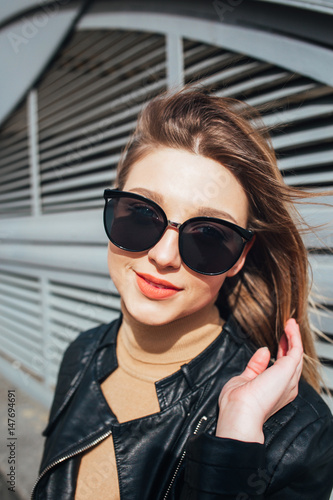 Fashion portrait pretty woman in black rock style in sunglasses over gray background in city © Elena Kratovich