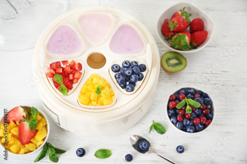 Modern yogurt maker and ingredients on wooden table