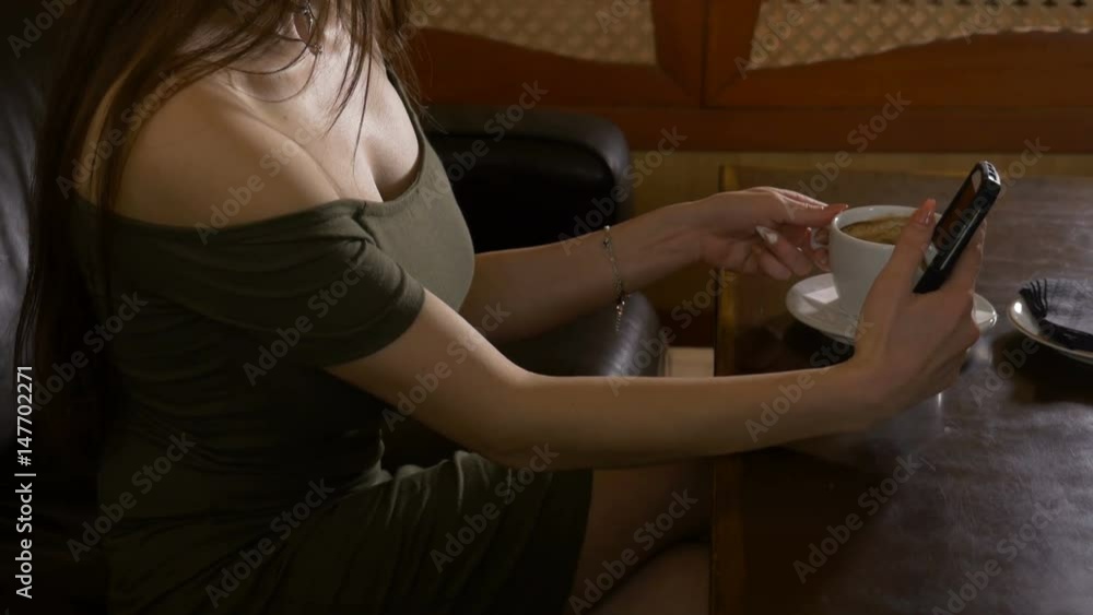 Attractive young woman sitting at a table alone in coffee shop and taking selfies Attractive young woman sitting at a table alone in coffee shop and taking selfies
