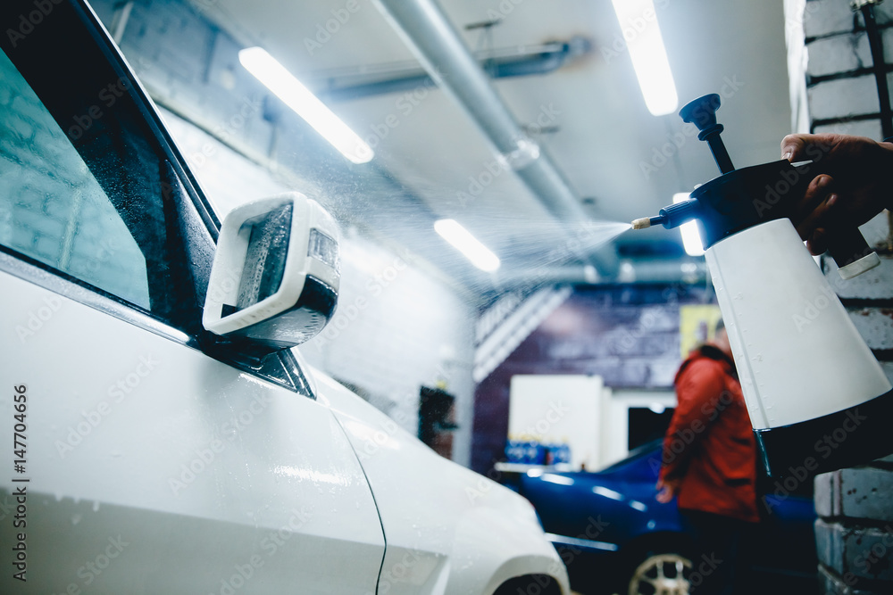 man working a car wash close up car cleans. Concept of washing a modern car with high-pressure water. man working a car wash close up car cleans. Concept of washing a modern car with high-pressure water.