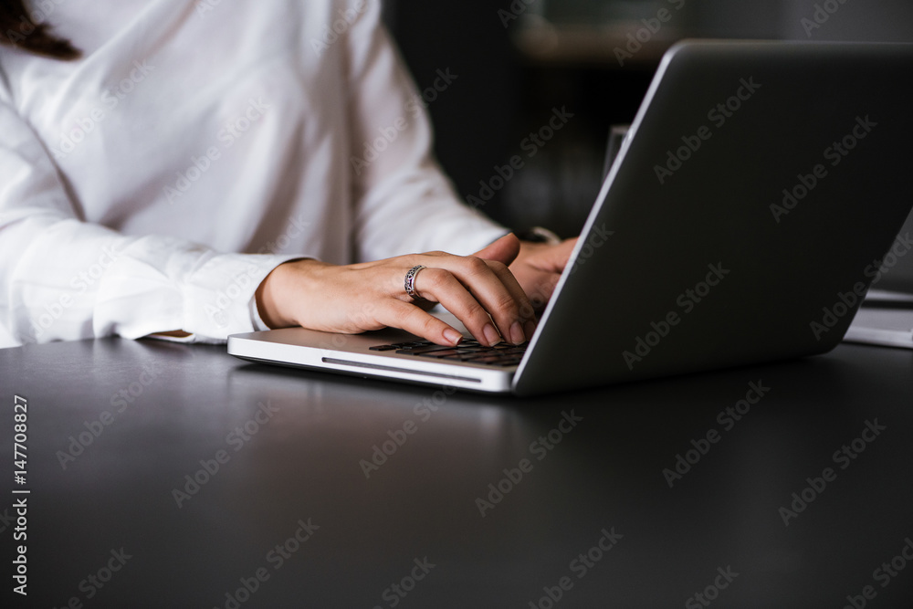 Side view and close up of woman's hands typing on laptop keyboard Side view and close up of woman's hands typing on laptop keyboard