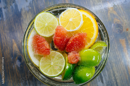 Citrus in water with bubbles in transparent plate Oranges, lemons, greyfrut, Pamela lemonade photo