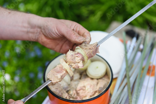 Man stringing meat on a skewer. Shashlik - cooking barbecue. Stringing meat on ramrod. photo