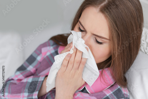Ill woman with tissue in bed at home