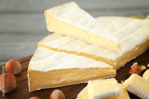 Sliced soft cheese and nuts on wooden board