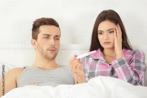 Surprised couple lying in b...