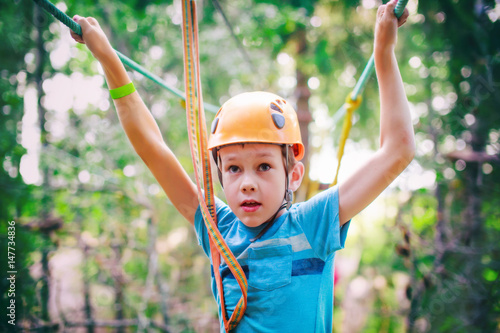 frightened boy in high wire park. kid ready to zip line flight in adventure park. zip lining. fear of heights