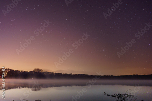 lights over a lake on a starry night © lakkot