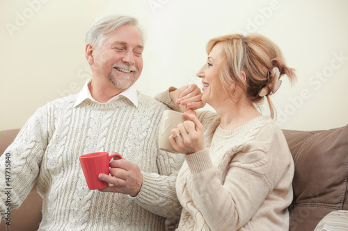 Cute elderly couple drinking tea at home