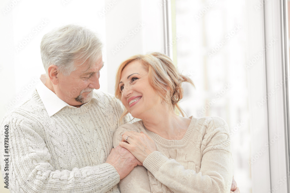 Cute elderly couple near window at home Cute elderly couple near window at home