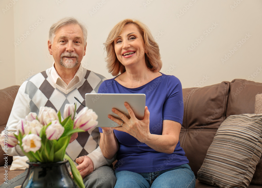 Cute elderly couple with tablet computer at home