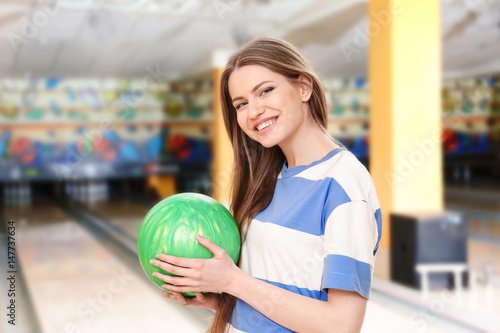 Beautiful young woman with ball in bowling club