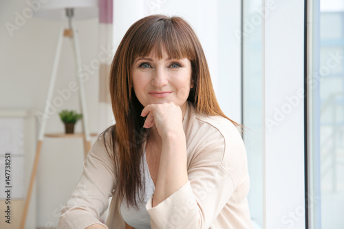 Beautiful mature woman near window at home