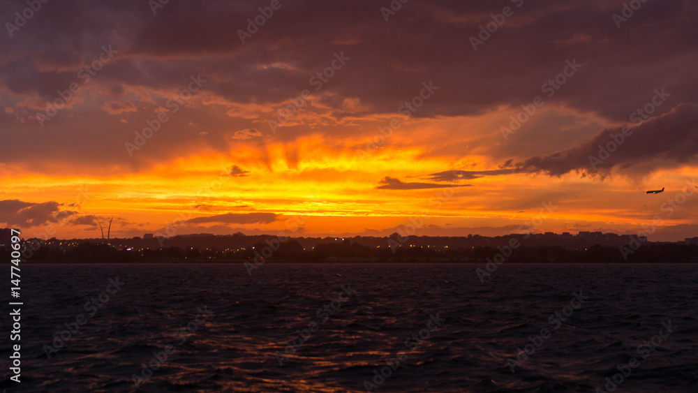 A brilliant orange sunset and crepuscular rays appears in the skies over the Potomac River as storms moved through the Washington, D.C. area.