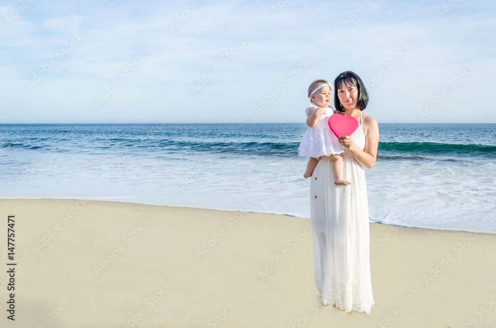 Mother and her baby girl on the sandy beach