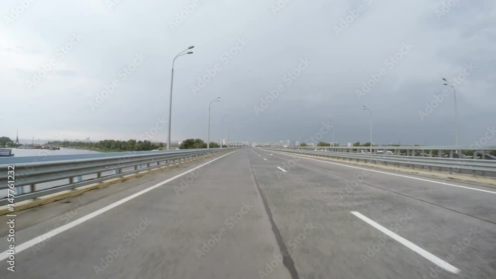 The car is driving along high speed highway an empty lane. The counter lane stands in the traffic jam. Rear view. The storm clouds in the sky. The car is driving along high speed highway an empty lane. The counter lane stands in the traffic jam. Rear view. The storm clouds in the sky.