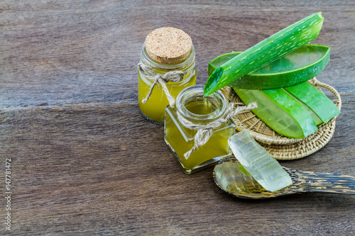 Fresh aloe vera gel on wooden spoon with aloe vera essential oil on wooden table