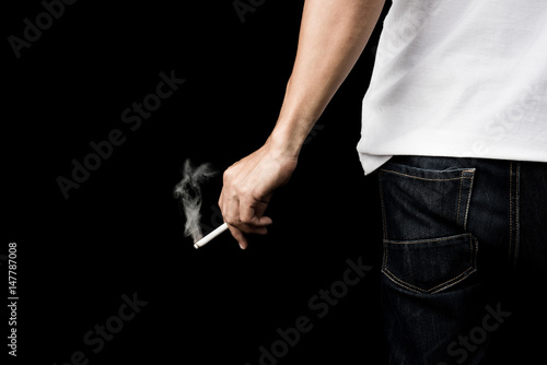 Hand of man holding cigarette with smoke on black background