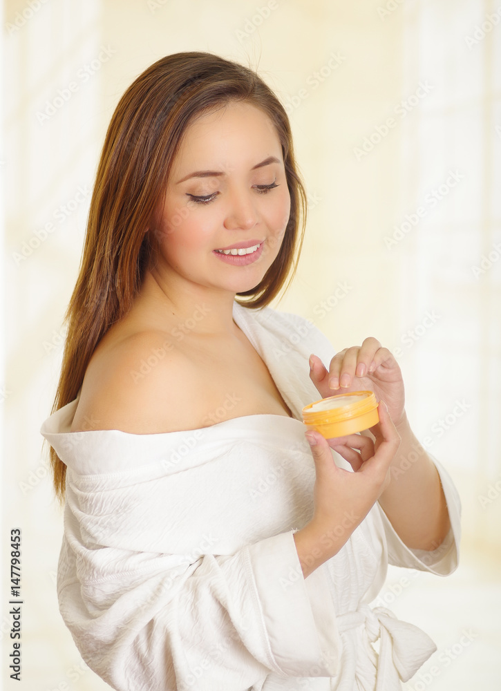 Beautiful smiling young woman adding a cream body over her shoulder