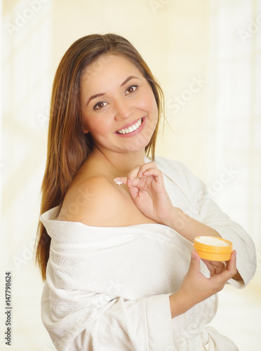 Beautiful smiling young woman adding a cream body over her shoulder