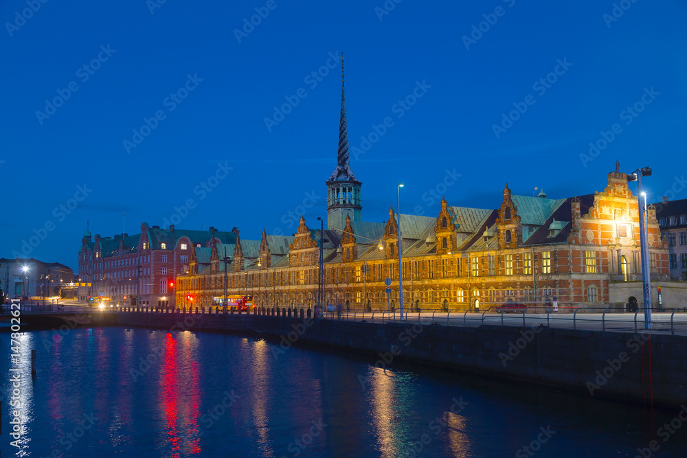 Obraz premium Old Stock Exchange at night in Copenhagen, Denmark. Former stock exchange building along the canal with a distinctive spire.