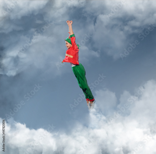 A boy dressed in Peter's Pan costume flying in a sky. © Fxquadro