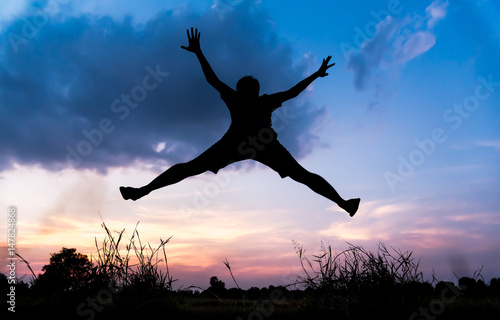 Silhouette young man relaxing with jumping over rice field in sunset sky outdoor.