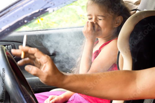 Stop smoking for children. Father smoking cigarette and the child choking of smoke in a car photo