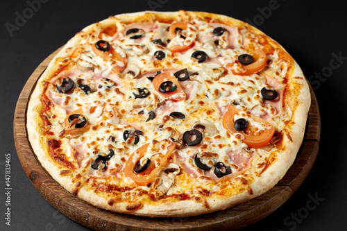 Hot pizza Regina on a rustic wooden table.