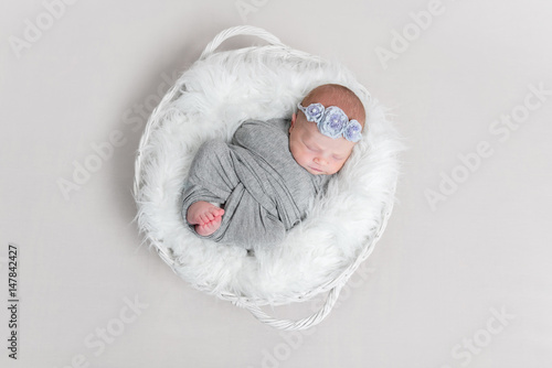 baby wrapped in blanket, in white basket, topview