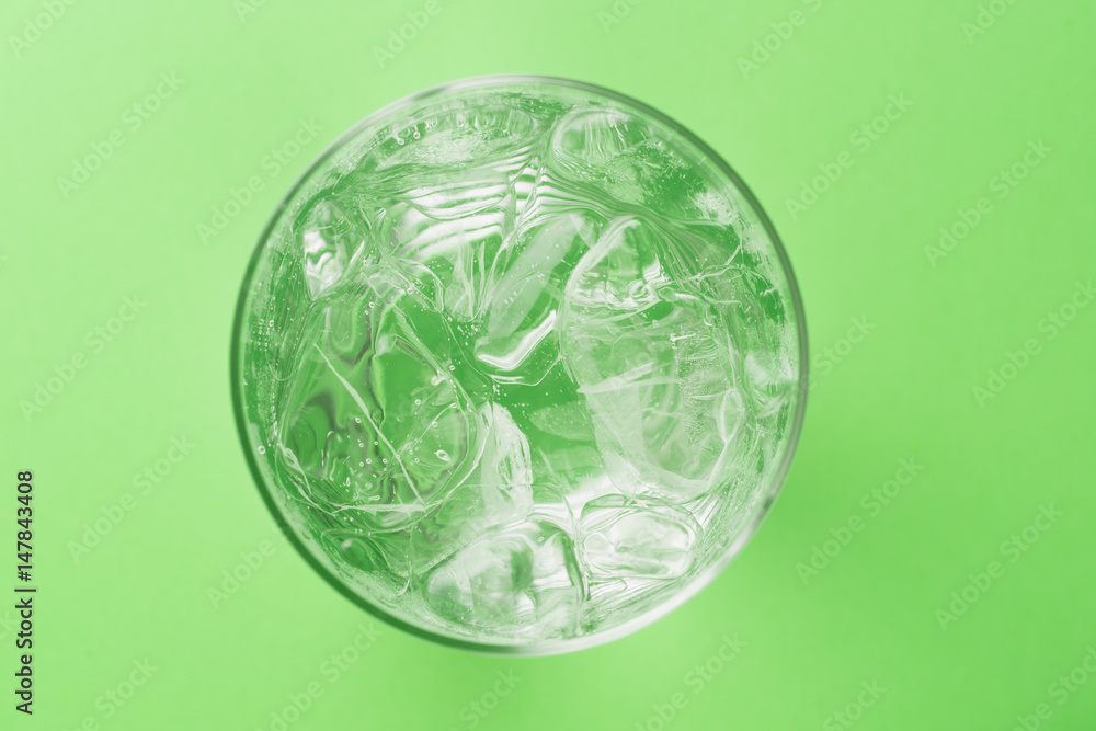 glass of soda with ice blocks isolated on green background, top view