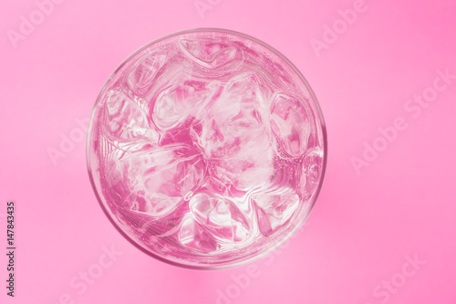 glass of soda with ice blocks isolated on pink background  top view