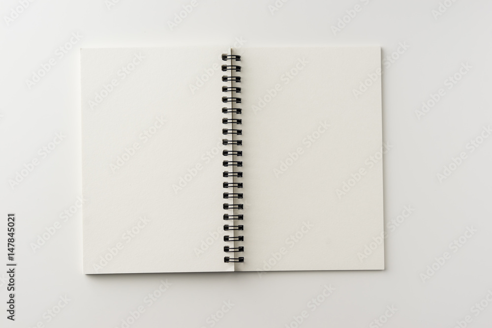 Business concept - Top view of spiral blank notebook on white background desk for mockup Business concept - Top view of spiral blank notebook on white background desk for mockup