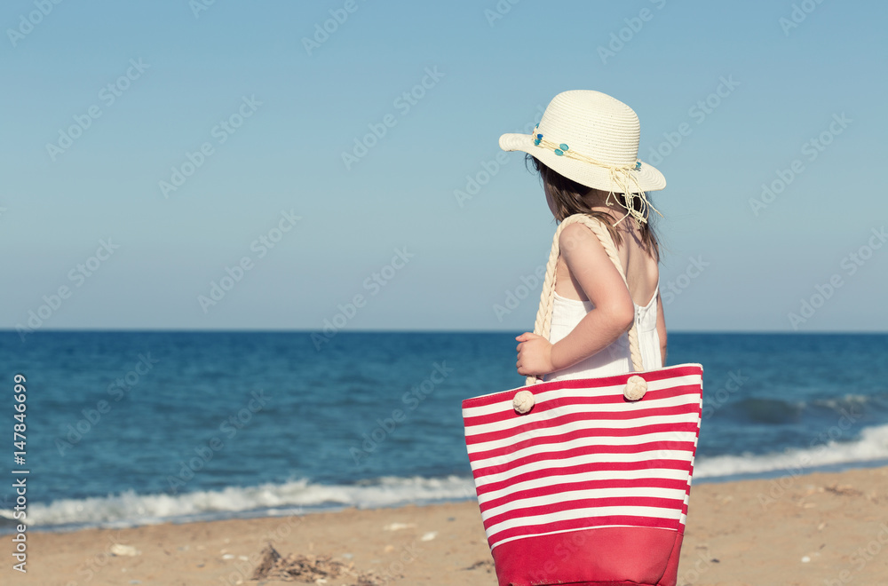 Little girl in white dress walking alone the sea, playing on the seashore Little girl in white dress walking alone the sea, playing on the seashore