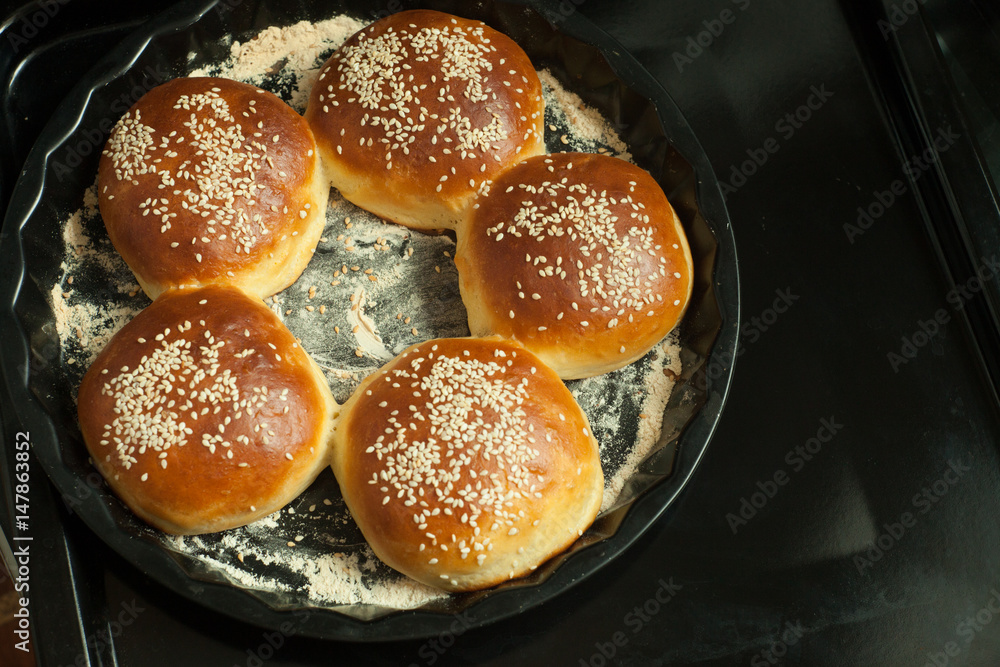 buns for burgers with sesame in a baking form on black background, copy space buns for burgers with sesame in a baking form on black background, copy space