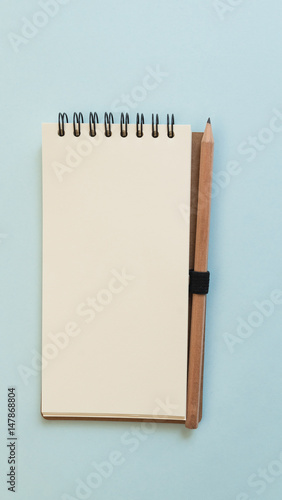 Blank notebook with pencil on blue background, view from above