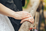hands of newlyweds with rings on the railing of the bridge