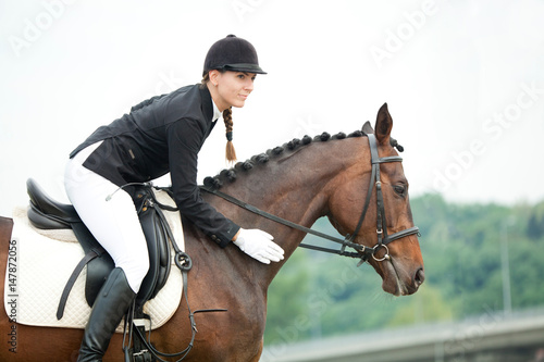 Attractive Young Woman in Jockey Helmet Stroking her Horse © AlexanderNovikov