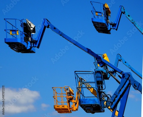 Wallpaper Mural A group of cherry pickers in the air seen from the side,  against a blue sky with some coluds Torontodigital.ca