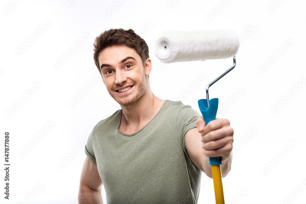 handsome man holding paint roller and looking at camera isolated on white, handyman tools concept handsome man holding paint roller and looking at camera isolated on white, handyman tools concept