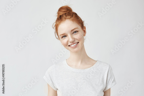 Portrait of young beautiful ginger woman with freckles cheerfuly smiling looking at camera. Isolated on white background. Copy space.