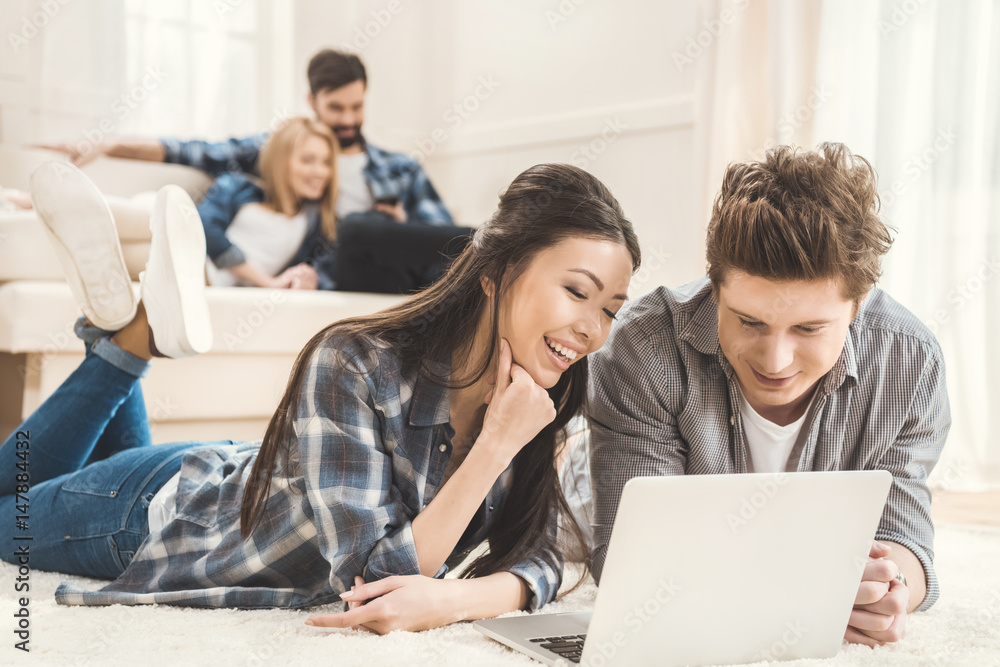 couple laying on carpet and using laptop couple laying on carpet and using laptop