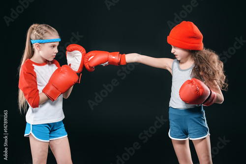 side view of sportive girls pretending boxing isolated on black, active kids concept © LIGHTFIELD STUDIOS