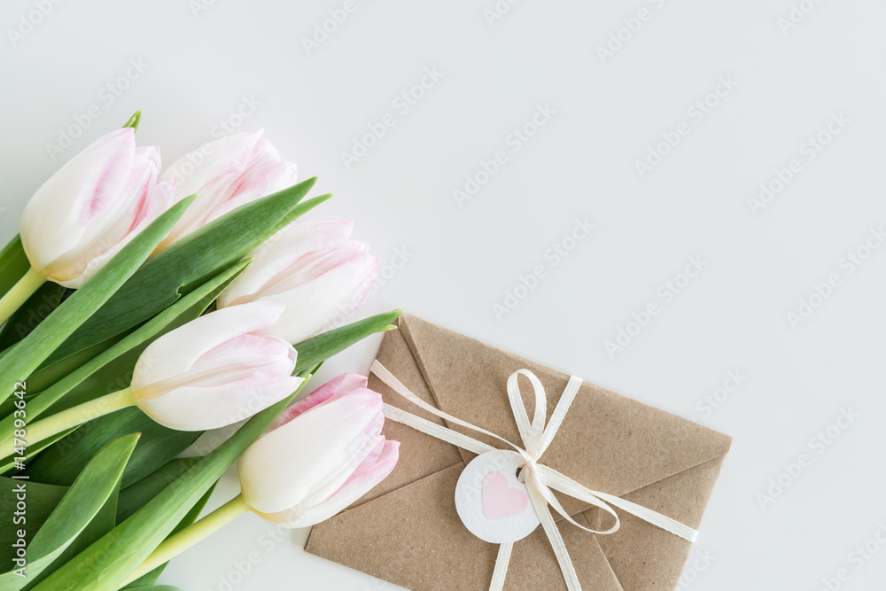light pink tulips and envelope isolated on white with copy space, wedding cards flowers concept light pink tulips and envelope isolated on white with copy space, wedding cards flowers concept