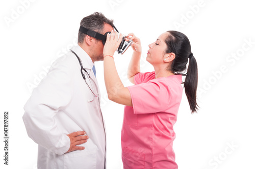 Female nurse putting futuristic gadget on medic head