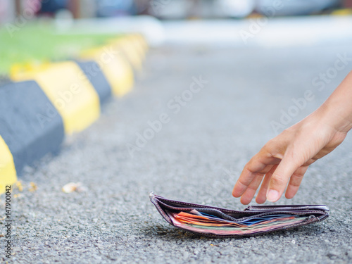 Close-up Of A Woman Picking Up Fallen Wallet On road side