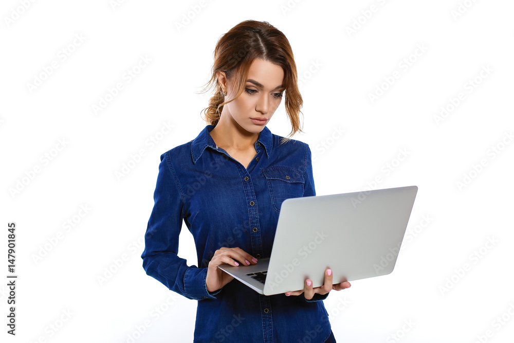 Focused on work. Confident young beautiful woman in shirt working on laptop, standing on white background Focused on work. Confident young beautiful woman in shirt working on laptop, standing on white background