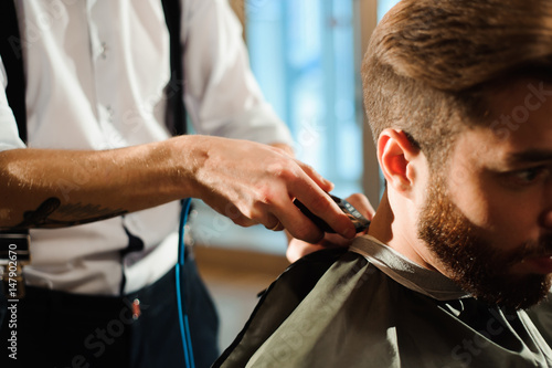 Master cuts hair and beard of men in the barbershop