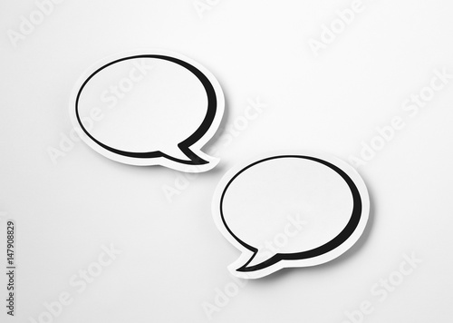 2 blank speech bubbles on white paper background. Chat bubble cut from cardboard. Simple and effective design. Discussion, chat and commenting concept with a lot of free empty copy space for text.