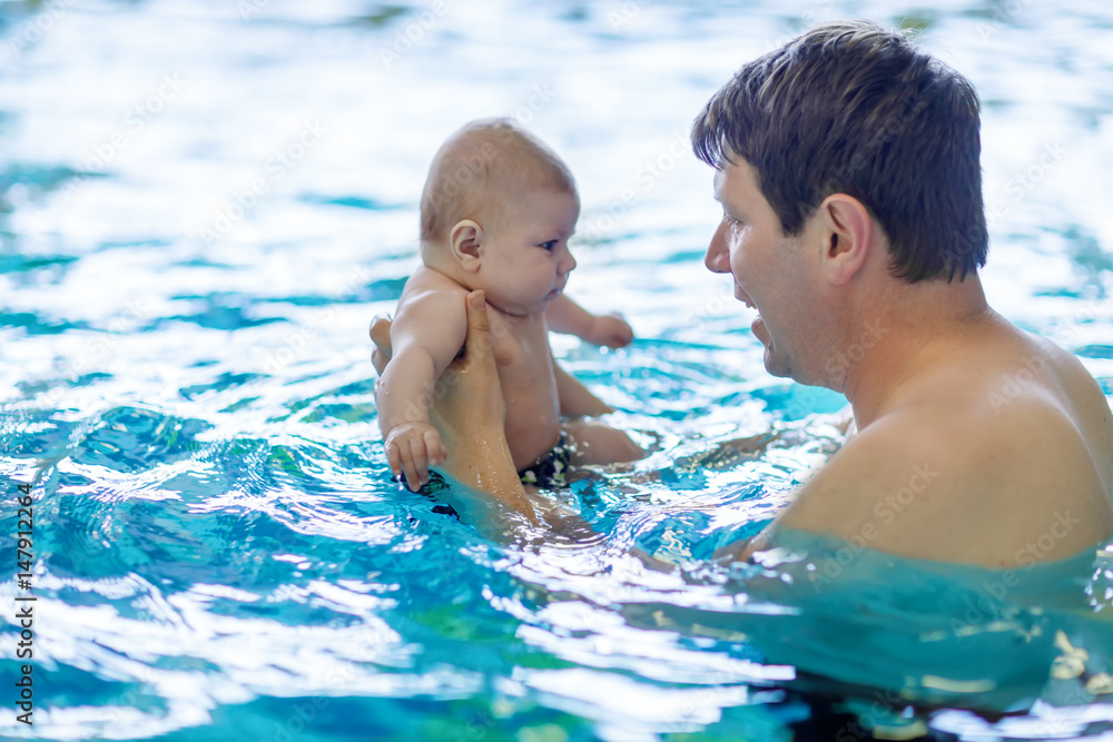 Happy middle-aged father swimming with cute adorable baby in swimming pool. Happy middle-aged father swimming with cute adorable baby in swimming pool.